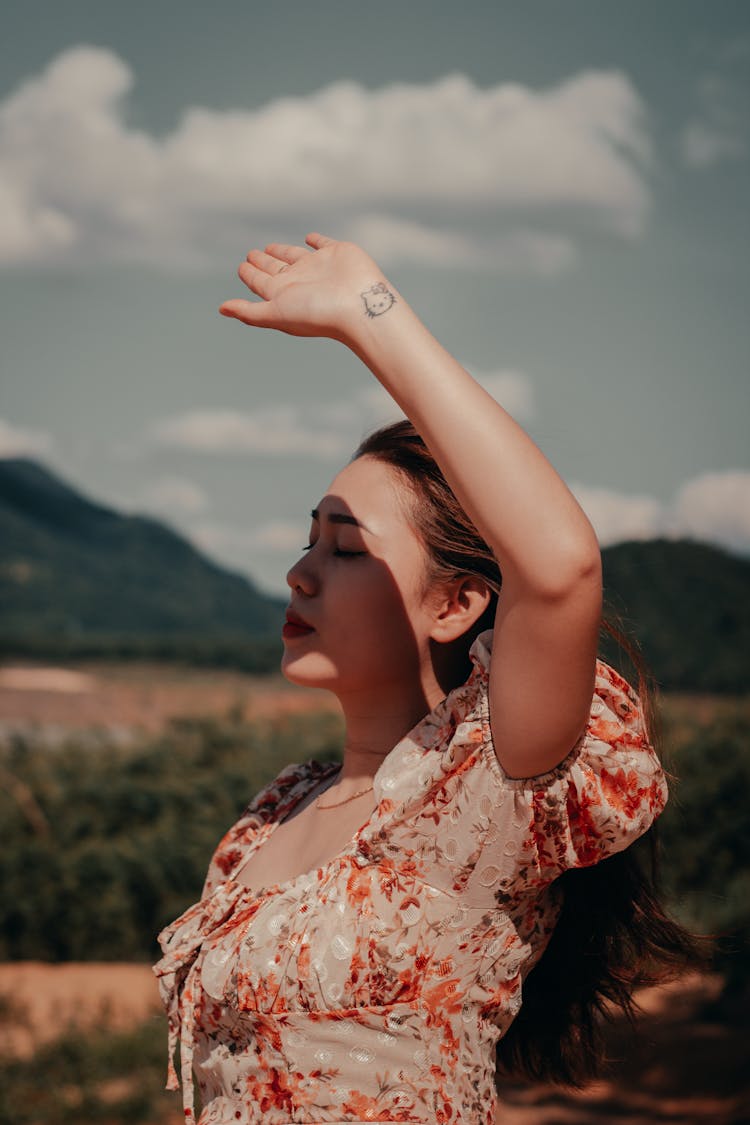 A Woman In White And Orange Floral Top Blocking The Light From Face