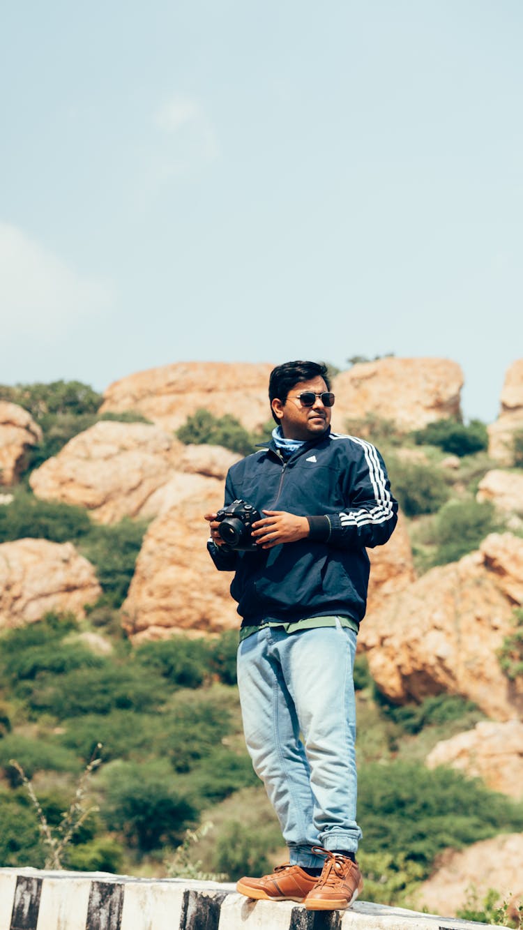 Man Standing On Ledge In Mountains