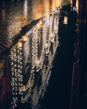 Street lights reflecting in a puddle at night, creating a mesmerizing urban scene.