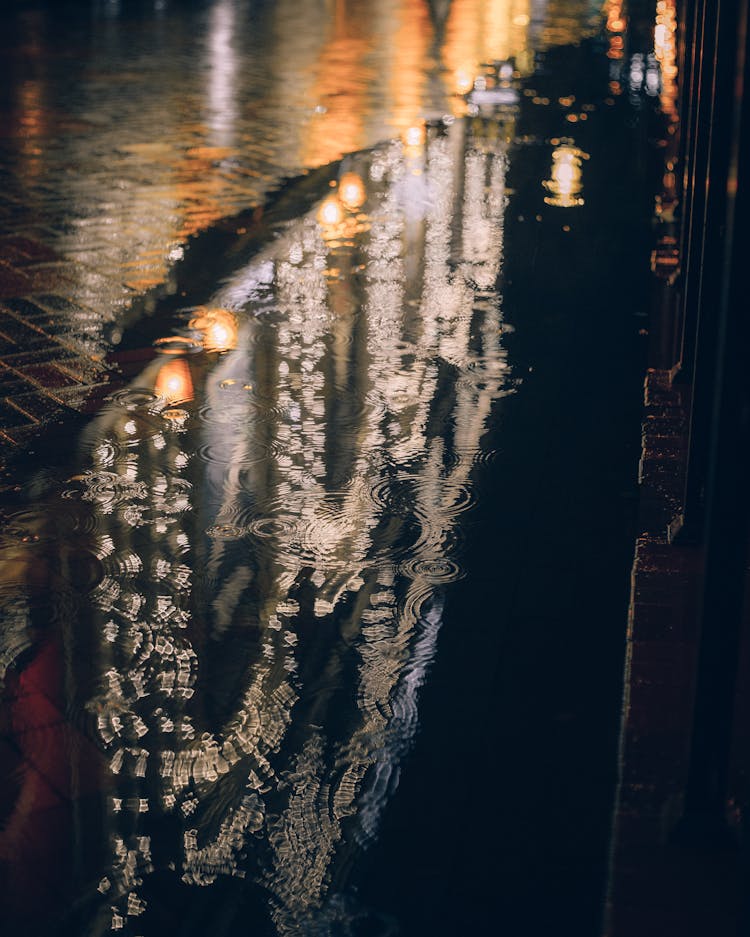 A Building Reflecting On A Puddle At Night