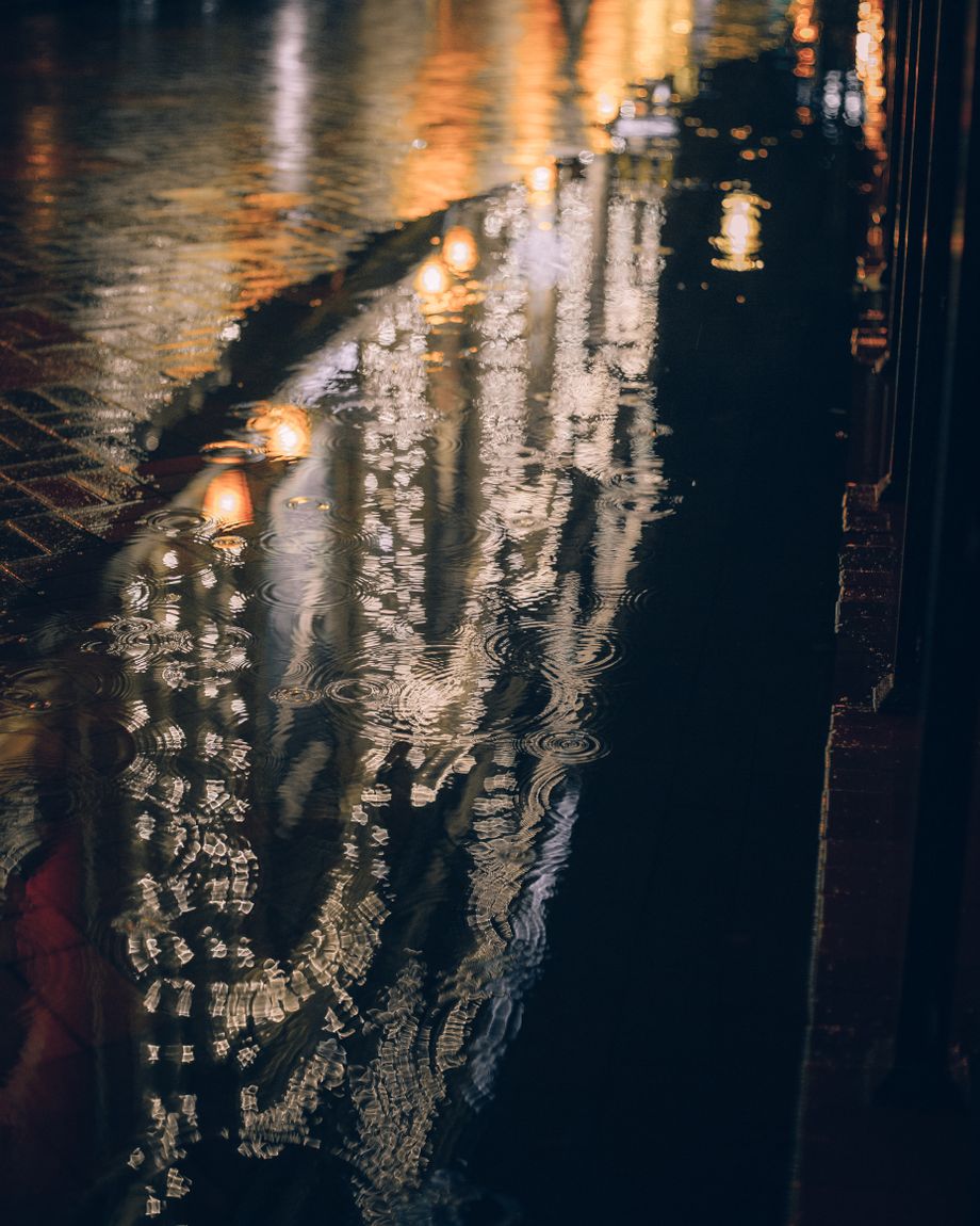 Wet city street reflecting street lamps after dark, photo by Yura Forrat on Pexels