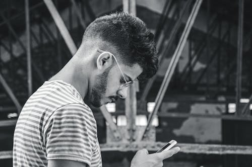 Free Grayscale Photo of a Man in Striped Shirt Using His Cellphone Stock Photo