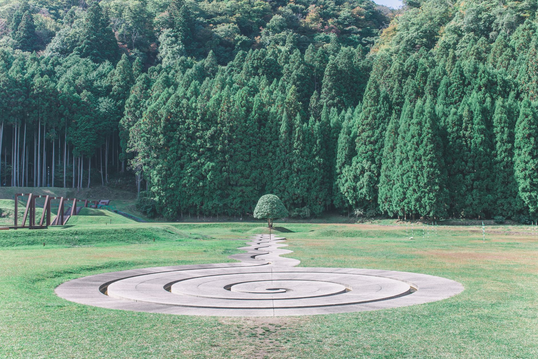 Captivating spiral artwork surrounded by lush green forest in outdoor setting.