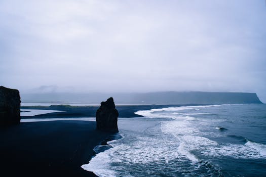 Stunning view of Iceland's black sand beach with rugged coastline and crashing waves.