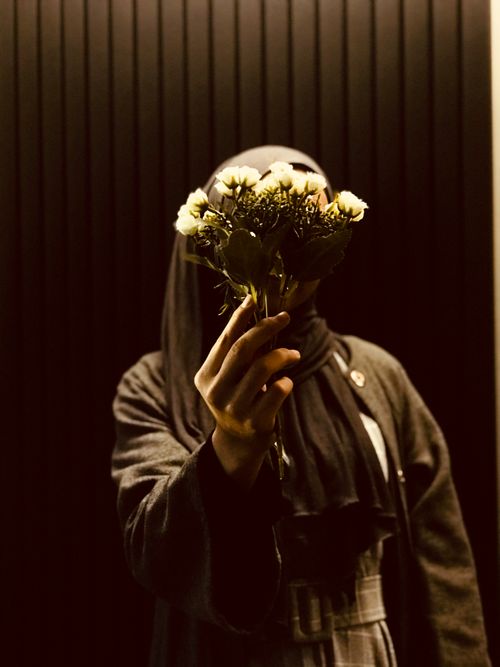 Free Artistic portrait of a person holding a bouquet, creating a mysterious and dark ambiance. Stock Photo