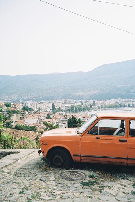 Explore Ohrid's beauty with a scenic view of an old car overlooking the city.