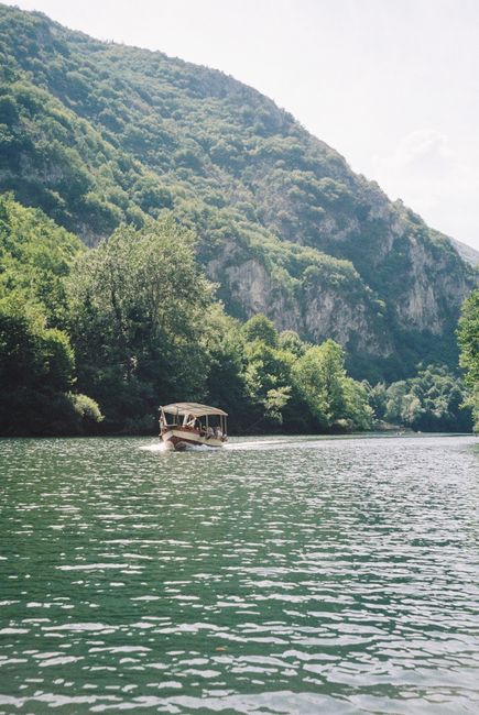 A peaceful boat journey on a river surrounded by lush green mountains under a clear sky.