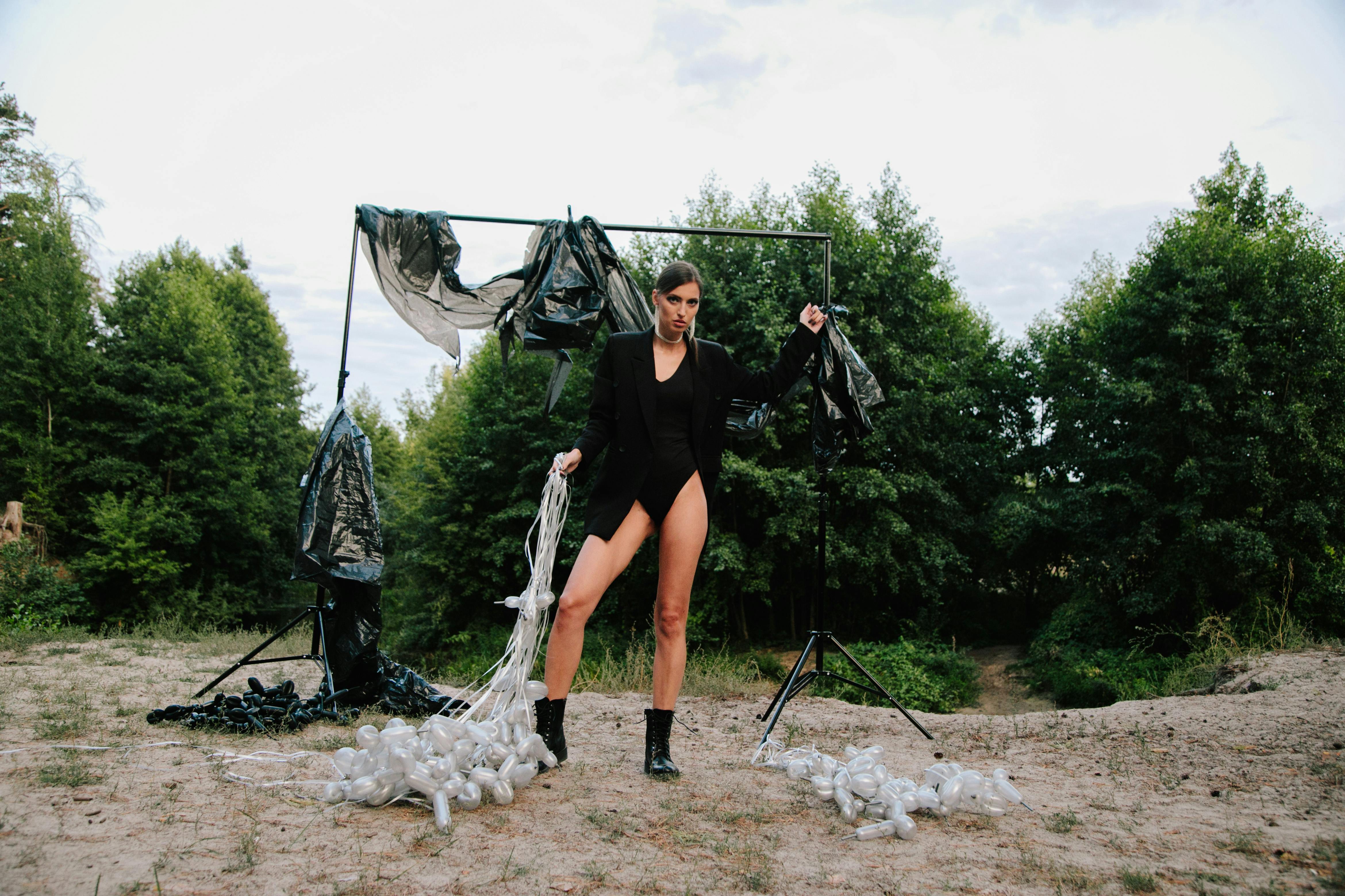 Model posing in front of a unique outdoor art installation in a forest setting.