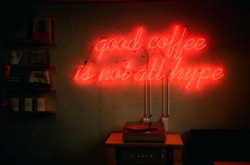 Free Neon sign 'good coffee is not all hype' with vintage turntable in a cozy setting. Stock Photo