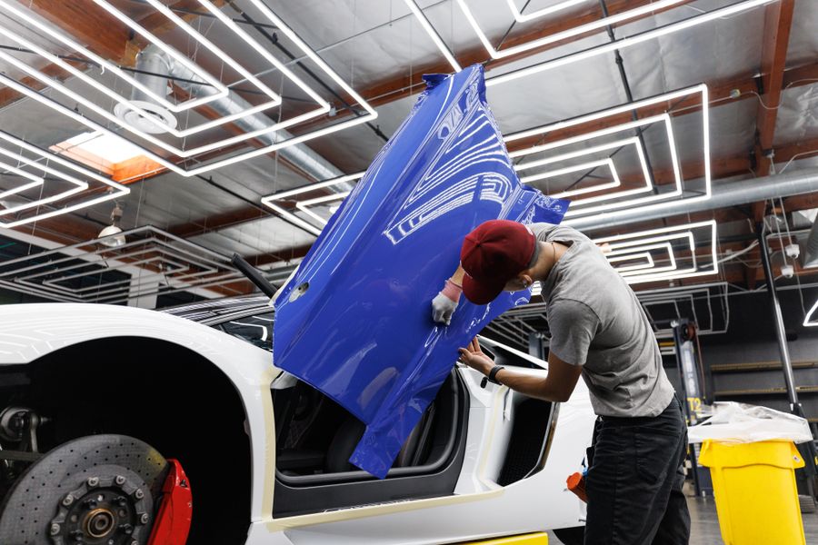 Mechaniker appliziert blaue Folierung an Fahrzeugtür