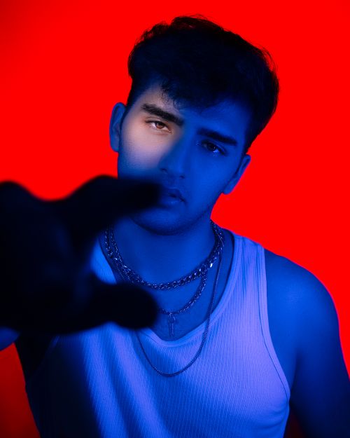 Free Dramatic portrait of a young man in a tank top, featuring bold red and blue lighting. Stock Photo