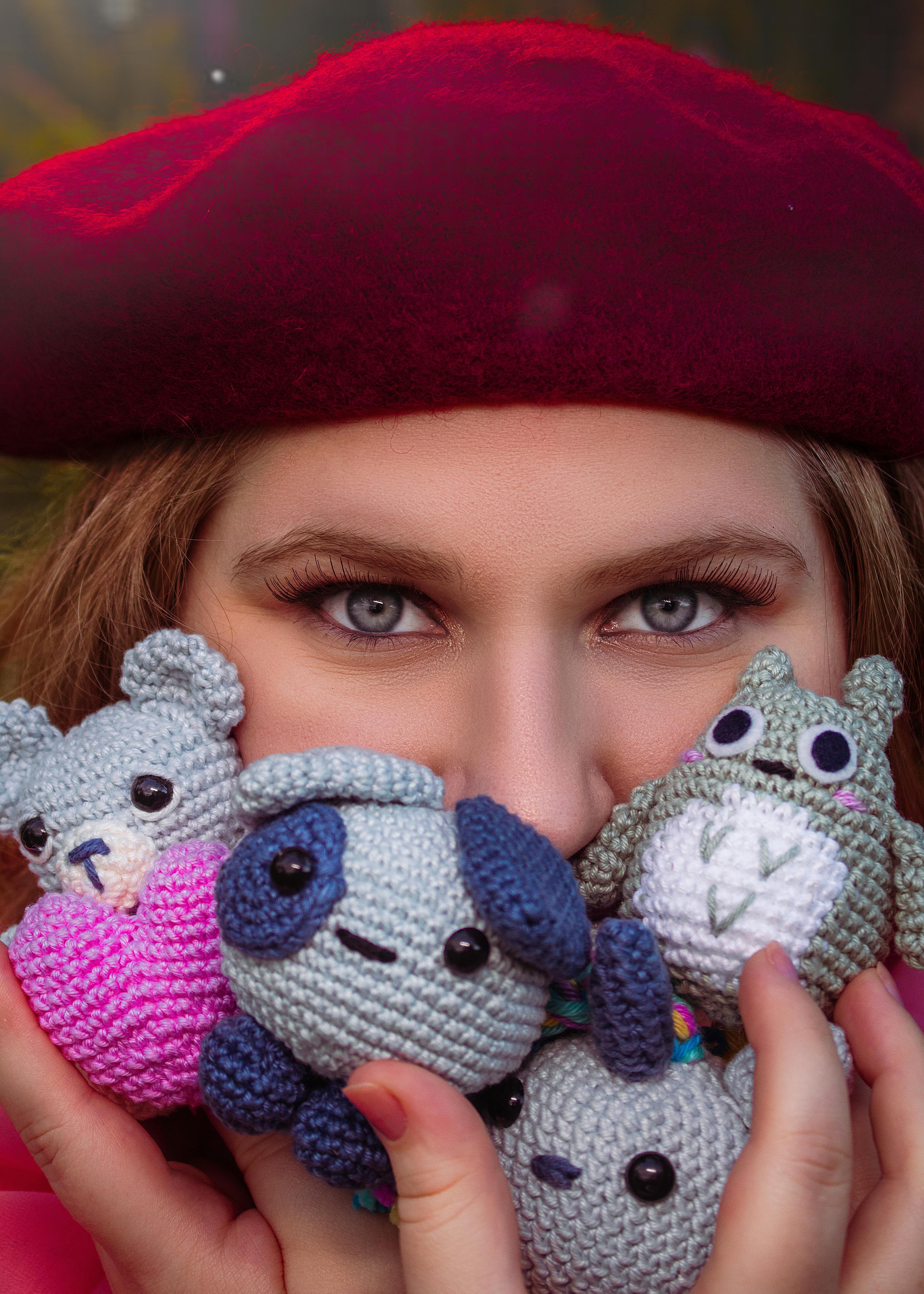 a woman in red beret holding gray knitted toys