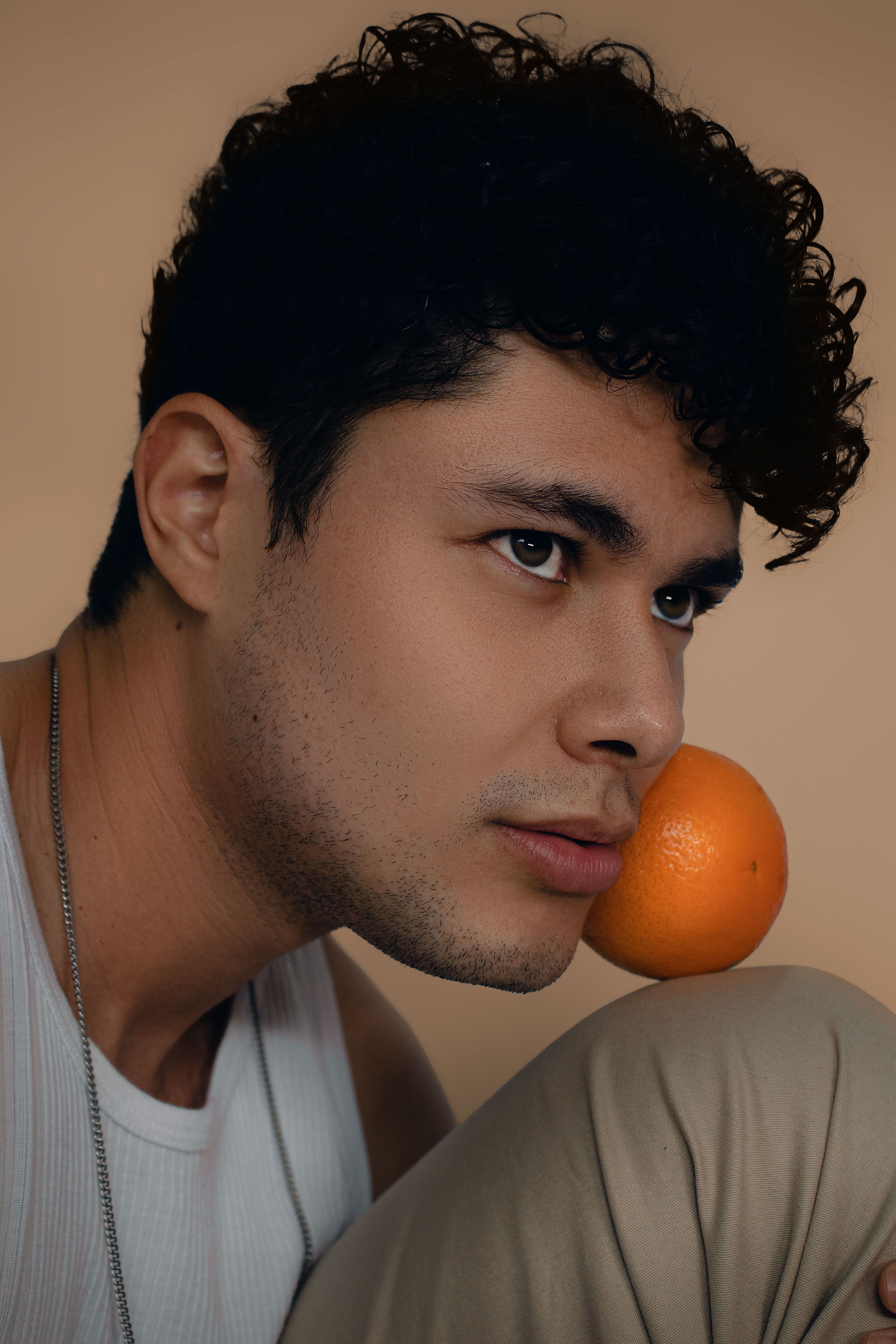 Unique studio shoot featuring a young man posing with an orange fruit.