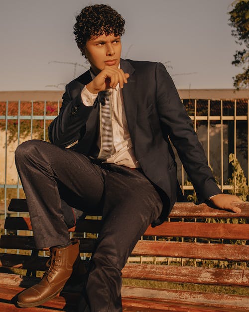 A Man in Black Suit Sitting on Brown Wooden Bench