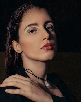A striking portrait of a woman with makeup in the rain, showcasing elegance and mystery at night.