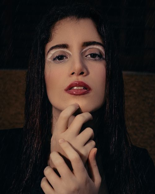 Free Close-up portrait of a woman with striking makeup and thoughtful pose. Stock Photo