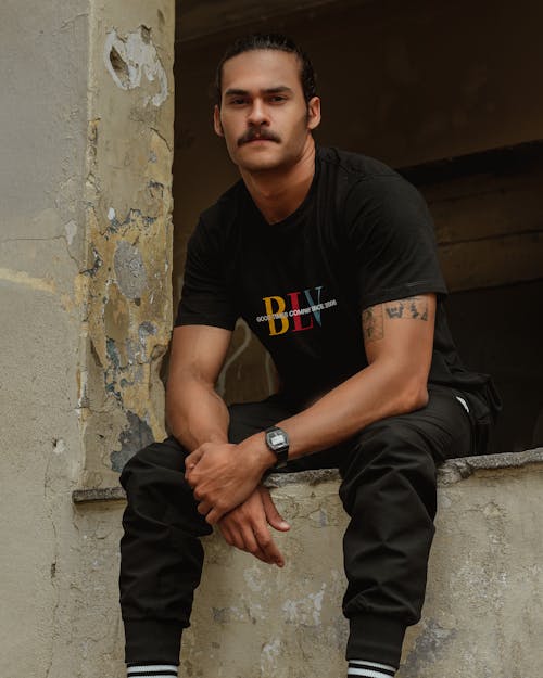 Man in Black T-shirt Sitting on a Window