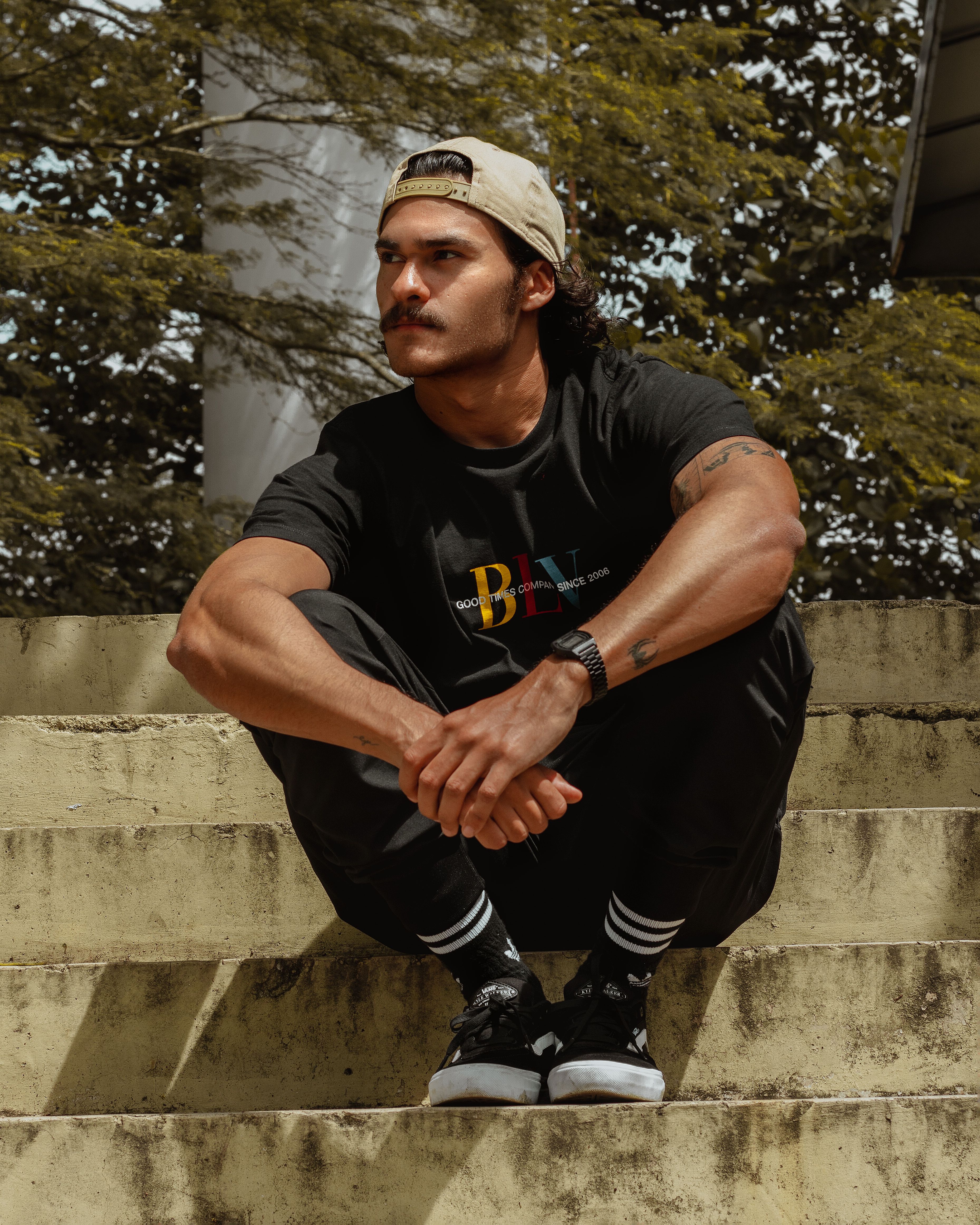 Stylish young man sitting on concrete steps with a serene expression, embracing street style fashion.