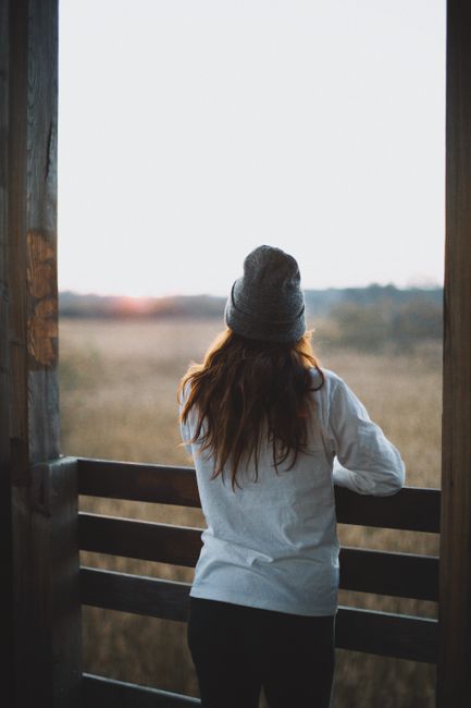 A woman in a beanie and white shirt overlooks the autumn landscape in Kampinos, Poland.