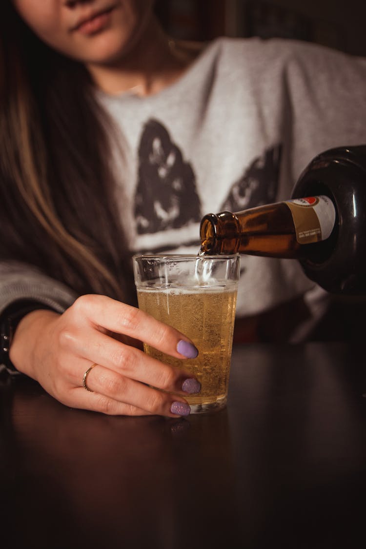 A Person Pouring Beer In The Glass