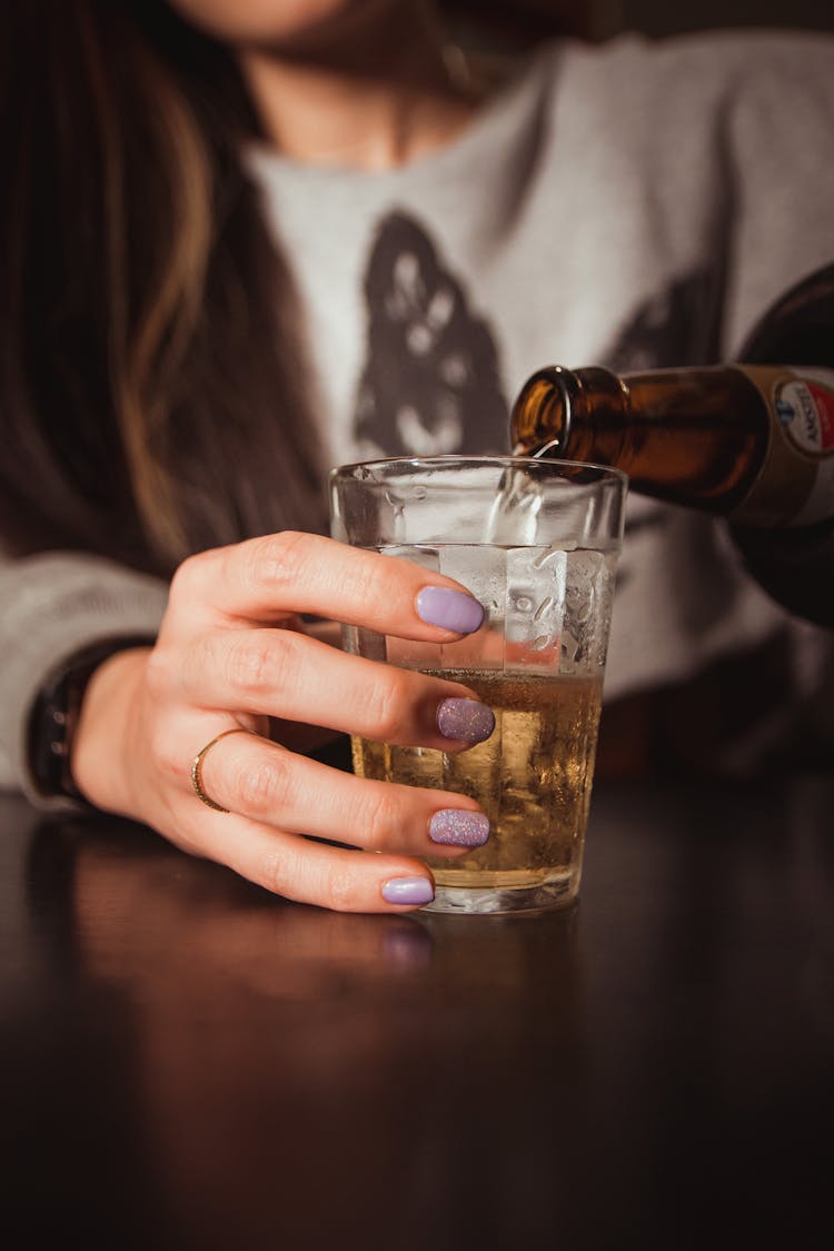 A Person Pouring Beer In The Glass