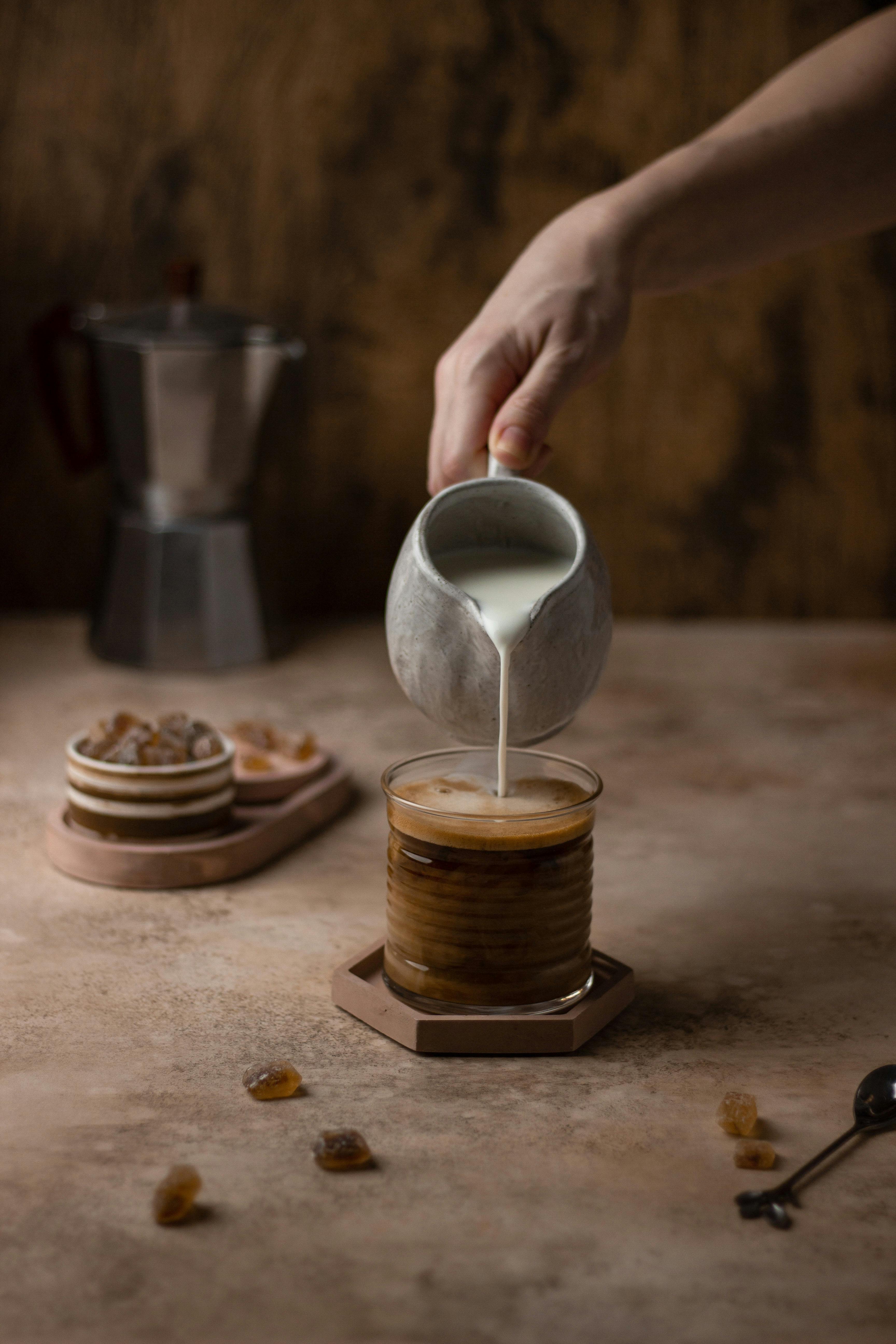 a person pouring a milk to a coffee