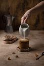 Person Pouring a Silver Cup to a Coffee