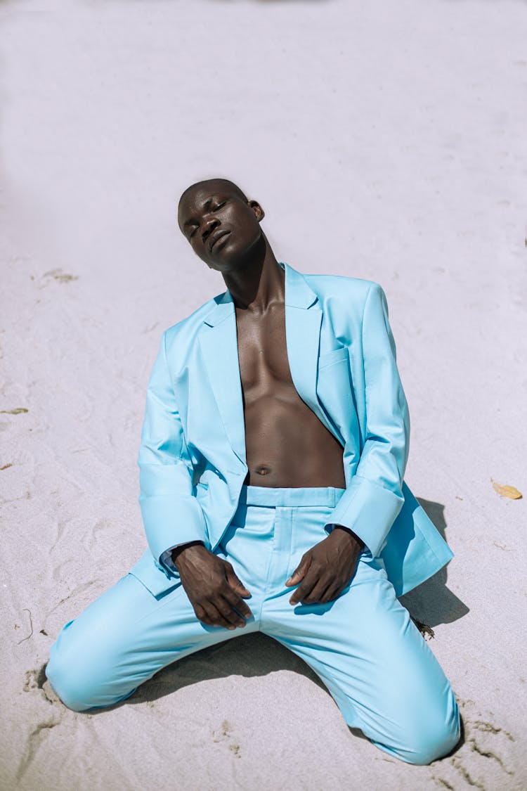 Shirtless Man In Blue Blazer And Pants Kneeling On Sand