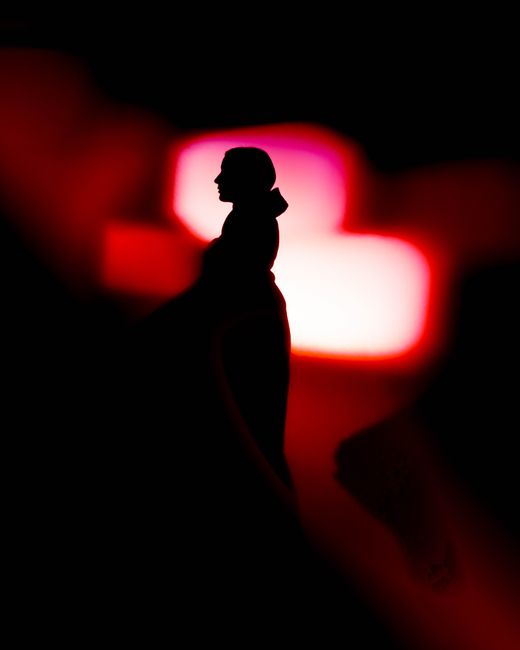Silhouette of a person set against bright red and pink neon lights creating a moody atmosphere.