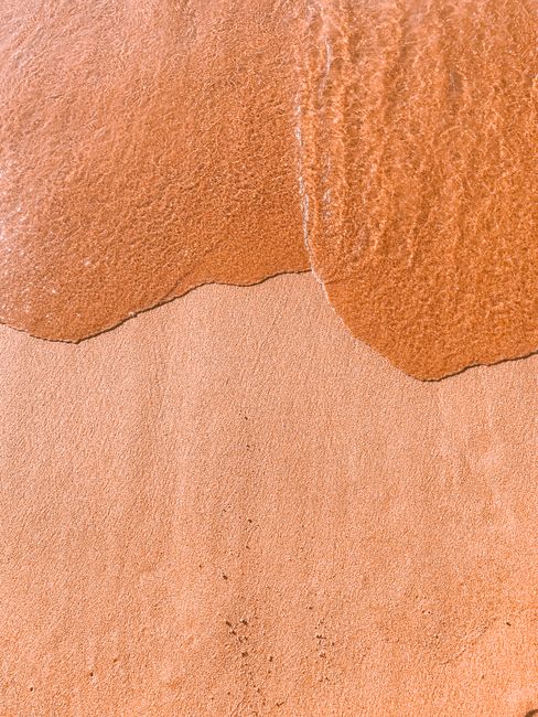 Calm sandy shore with gentle waves creating a soothing beach scene.