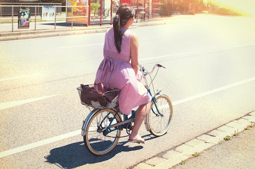 Donna In Vestito Viola Cavalcando Bicicletta Da Città Su Strada
