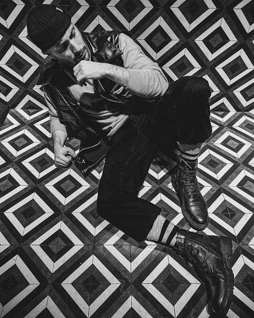 A Man Sitting on a Tiled Floor while Looking Afar