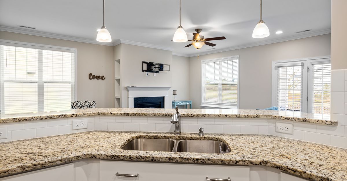 Bright kitchen interior featuring granite countertops, pendant lighting, and a spacious open layout.