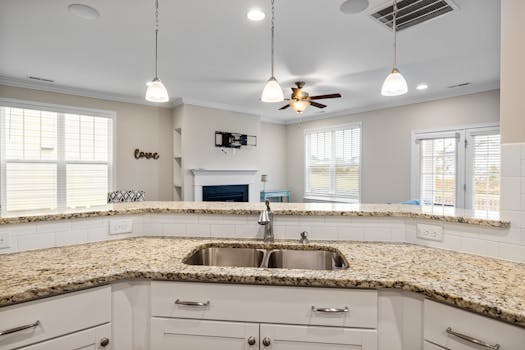 Bright kitchen interior featuring granite countertops, pendant lighting, and a spacious open layout.