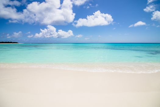 Discover the serene beauty of a pristine beach in Venezuela's Dependencias Federales, featuring turquoise waters and bright skies.
