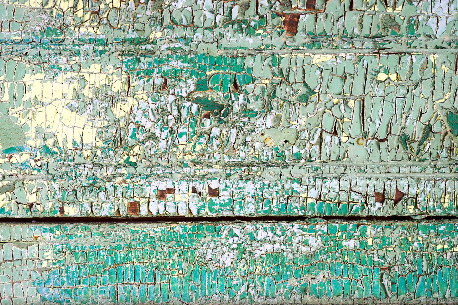 Close-up of a cracked mosaic wall showcasing intricate ceramic patterns and colors.