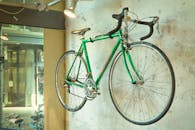 在城市环境中，商店的墙上挂着一辆老式绿色赛车自行车