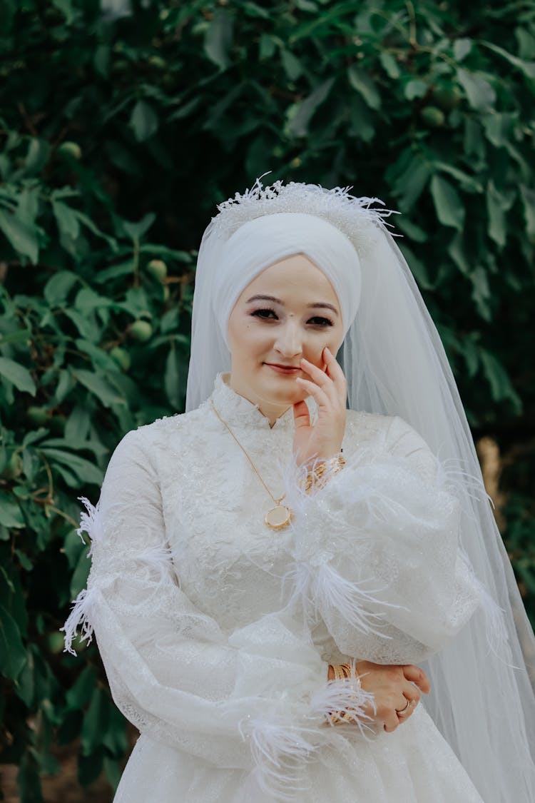 Bride In White Dress And Veil Touching Her Face With Hand