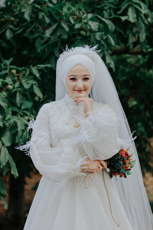 Smiling Bride Standing in Thoughtful Pose in Park or Garden