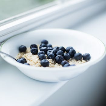 Delicious blueberries on creamy oatmeal in a white bowl by the window.