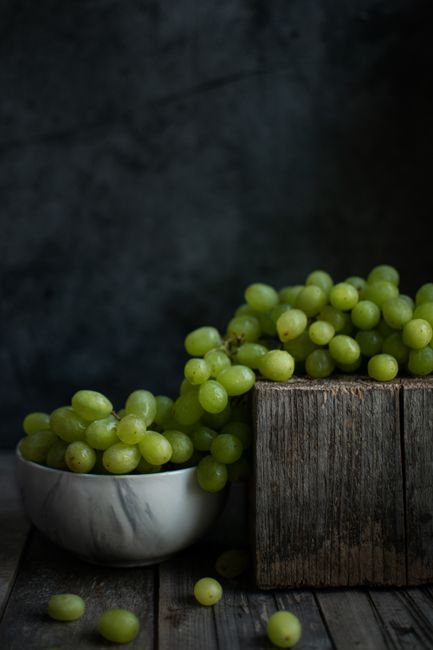 A bowl of vibrant green grapes elegantly arranged on a rustic wooden surface.