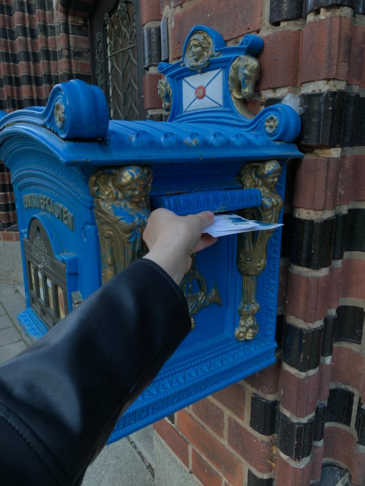 A Person Dropping Mails In The Mailbox