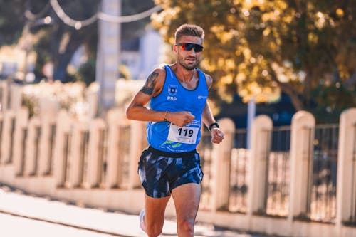 Free A Man in Blue Tank Top Running on the Road Stock Photo