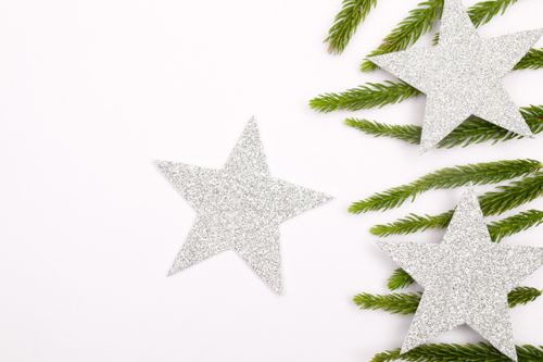 Free Silver star decorations on white background with pine branches for festive holiday theme. Stock Photo