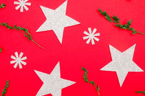 Free Silver stars and greenery on red background, perfect for holiday themes. Stock Photo