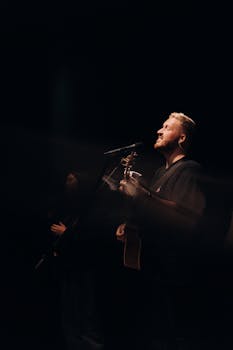 Two adult male musicians performing with guitars on stage with dramatic lighting.