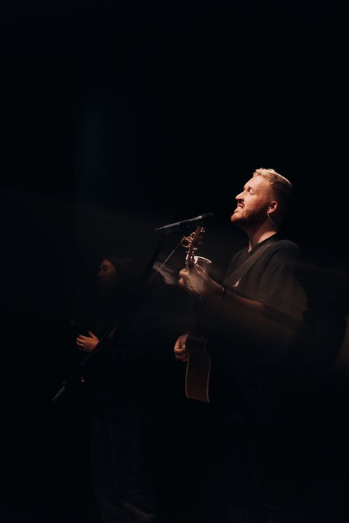 Free Two adult male musicians performing with guitars on stage with dramatic lighting. Stock Photo