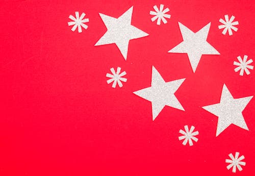 White Stars and Snow Flakes Paper Cut Outs on Red Surface