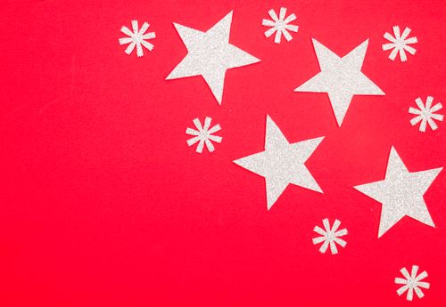 Free Sparkling glitter stars and snowflakes on a vibrant red background, perfect for holiday themes. Stock Photo