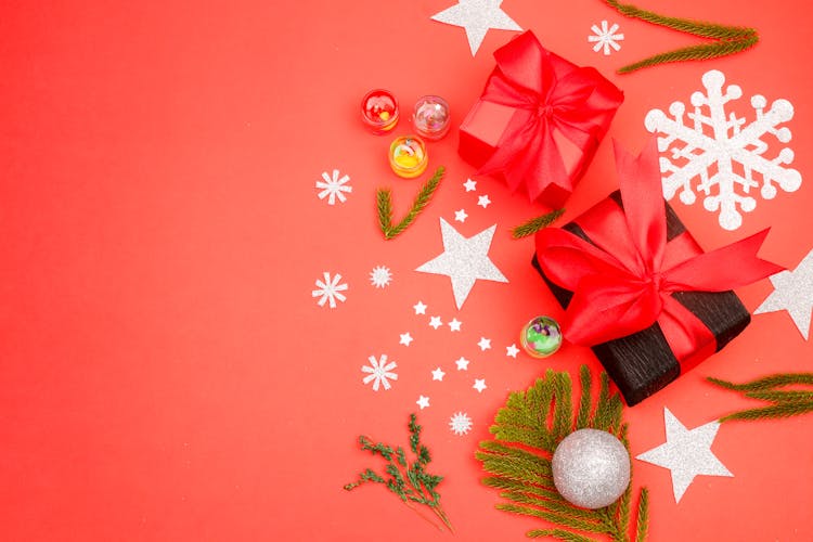 Paper Stars And Wrapped Gifts Lying On Red Background